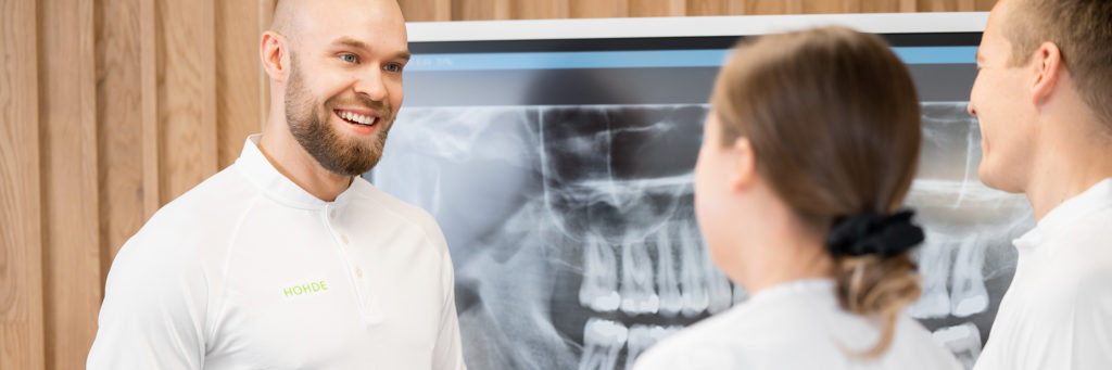 Kaksi hammaslääkäriä, taustalla röntgenkuva.